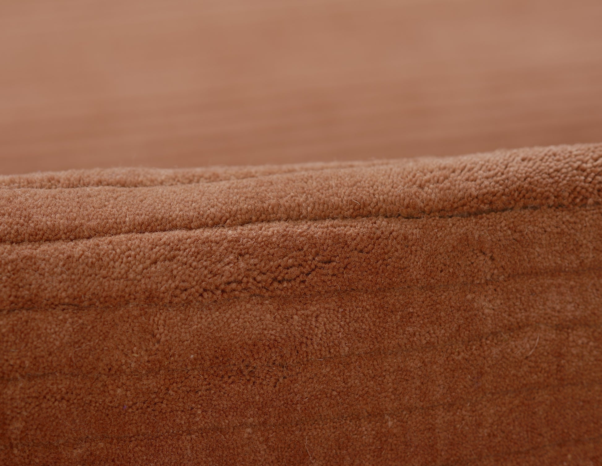 Close-up of brown suede-like fabric with folded edge and soft plush nap, ideal for a throw.