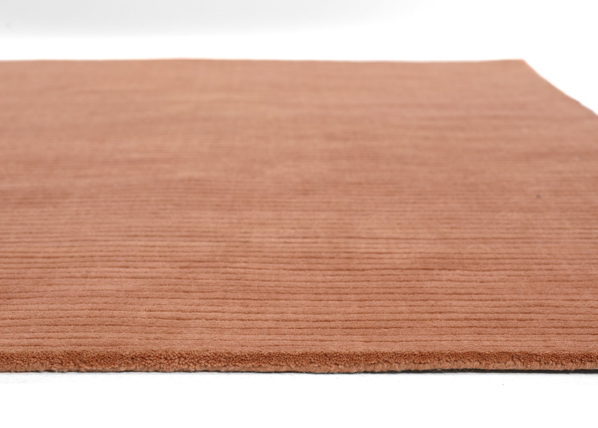 Rust terracotta rug with horizontal ribbed texture and soft plush pile.