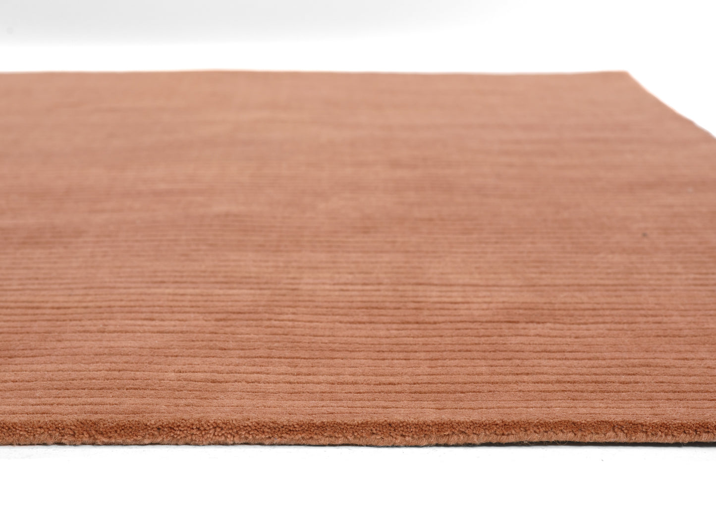 Terracotta rug with soft, ribbed pile and finished edge; warm orange-brown tones.