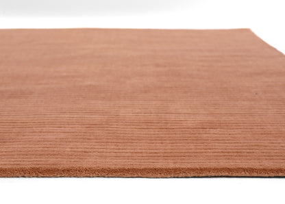 Terracotta brown textured rug with ribbed pile and fringed edge, rectangular shape.