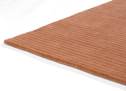 Peach ribbed bath mat in plush terry texture; rectangular bathroom rug.