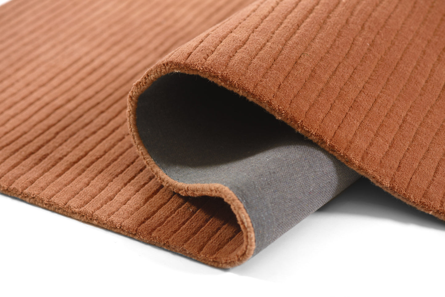 Rust-orange corduroy rug with ribbed texture and grey backing, folded at edge.