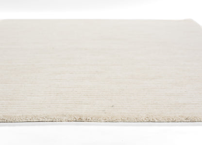 Cream-beige flat-weave rug with subtle linear texture, low pile and bound edge.