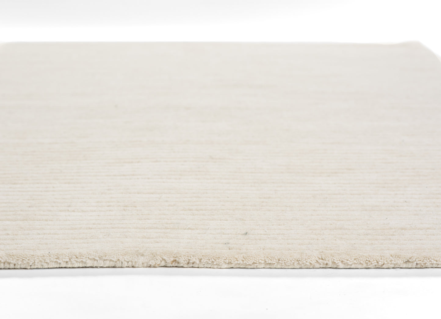 Cream-beige flat-weave rug with soft texture and short fringe along the edge.