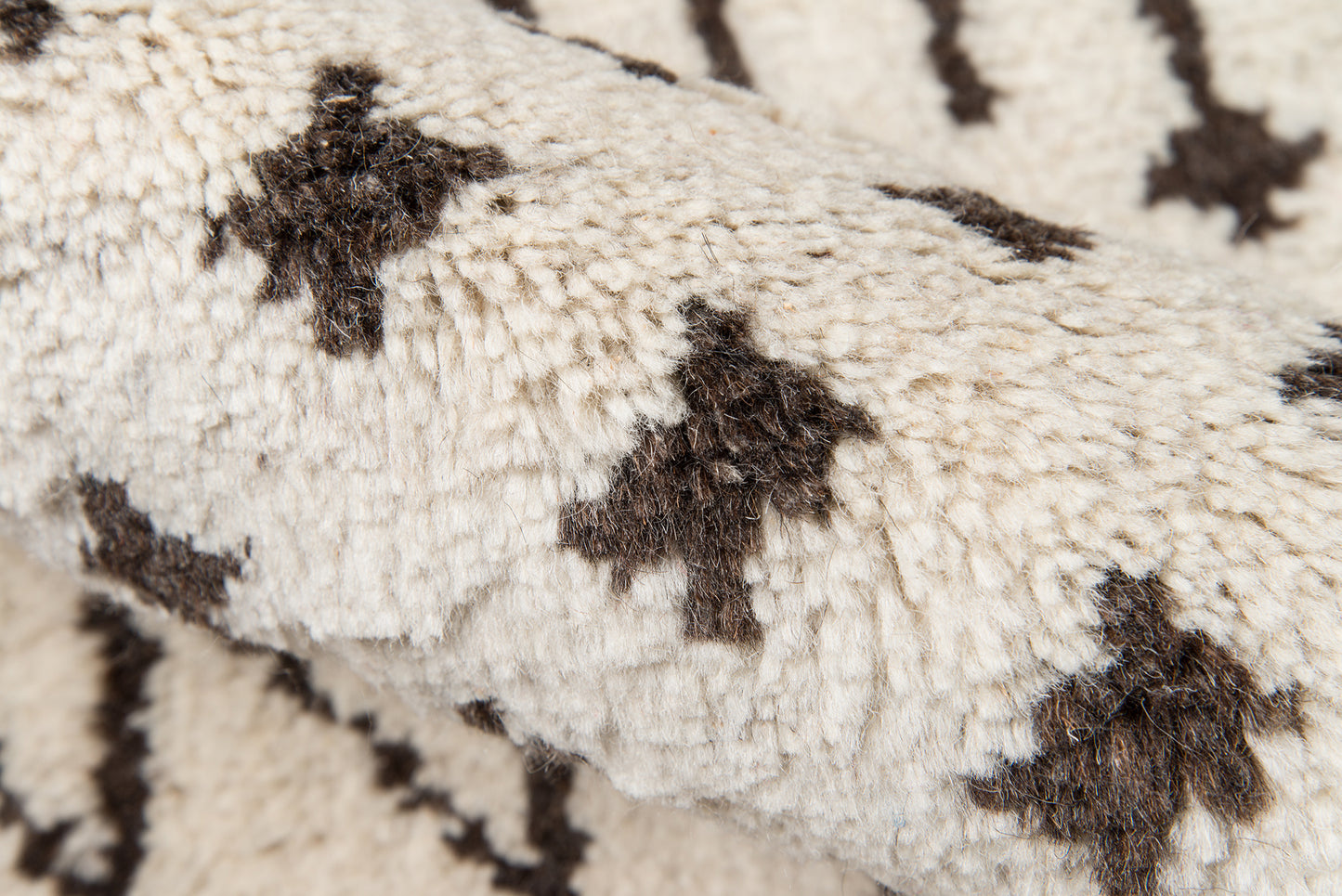 Cream shag rug with dark brown star-shaped motifs, plush pile and geometric tribal pattern.