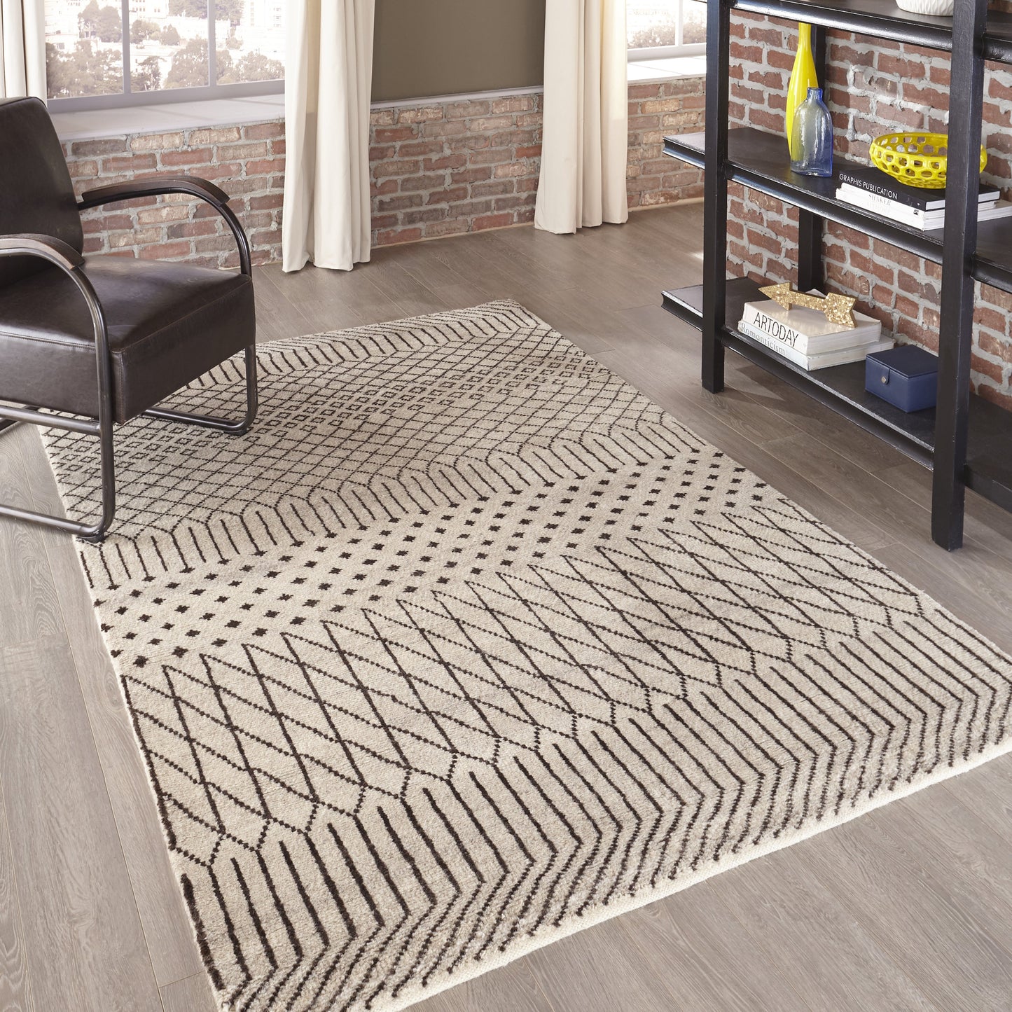 Natural beige area rug with black geometric chevron pattern in a modern industrial living room.