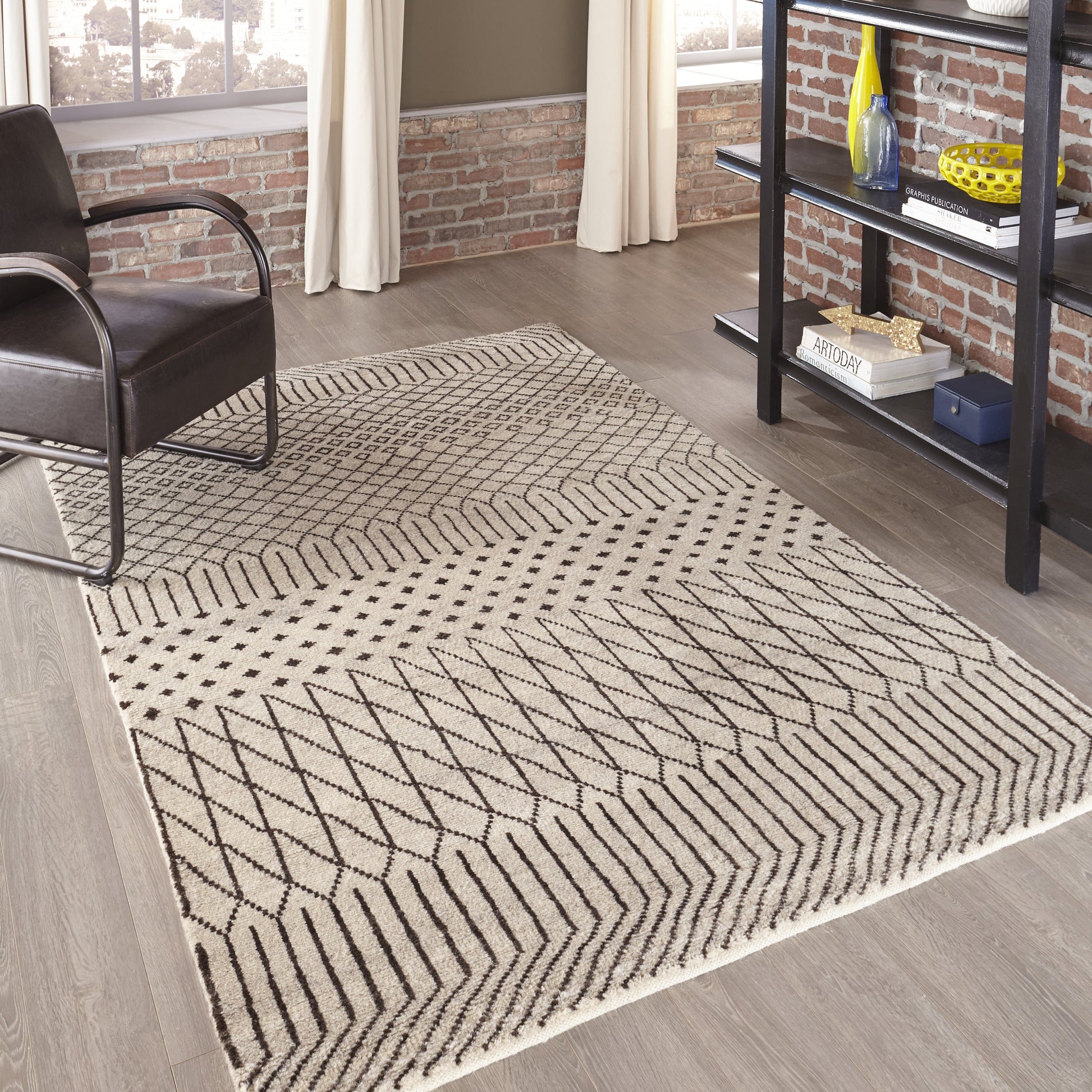 Natural beige area rug with black geometric chevron pattern in a modern industrial living room.