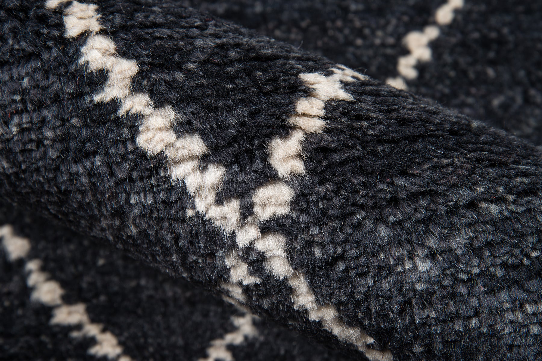 Dark navy shag rug with white chevron zigzag pattern; plush textured weave.