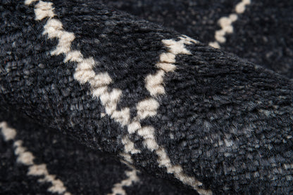 Close-up of navy plush rug with cream geometric lattice pattern and thick shaggy pile.