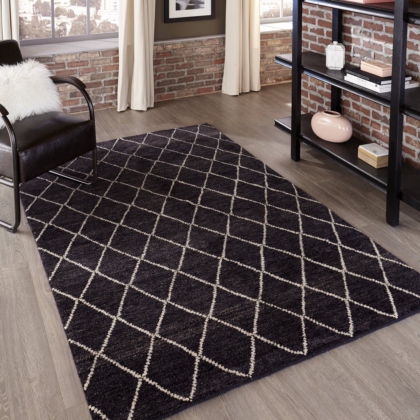 Charcoal shag rug with white diamond lattice in a modern living room with brick wall, black chair, and metal shelf.