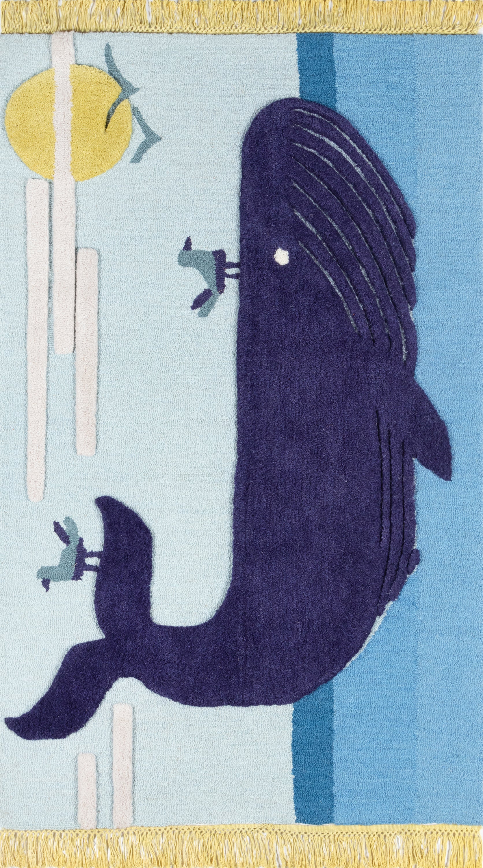 Purple whale silhouette rug on pale blue backdrop with sun motif, vertical bars, teal accents, yellow fringed edges.