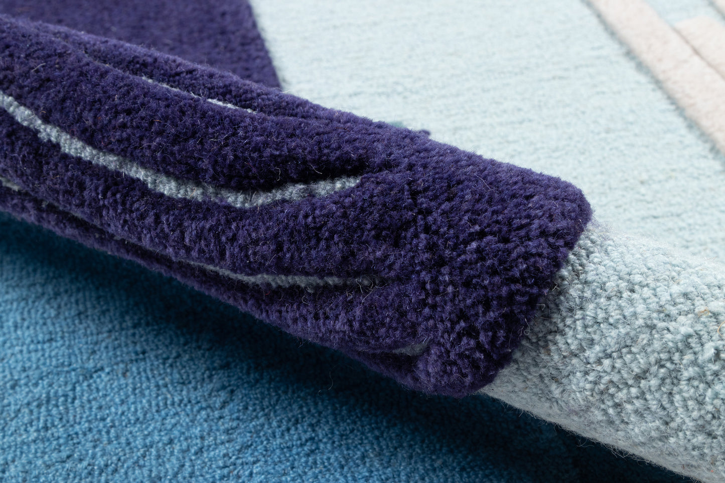 Dark purple plush rug with light blue stripe; close-up fluffy pile.