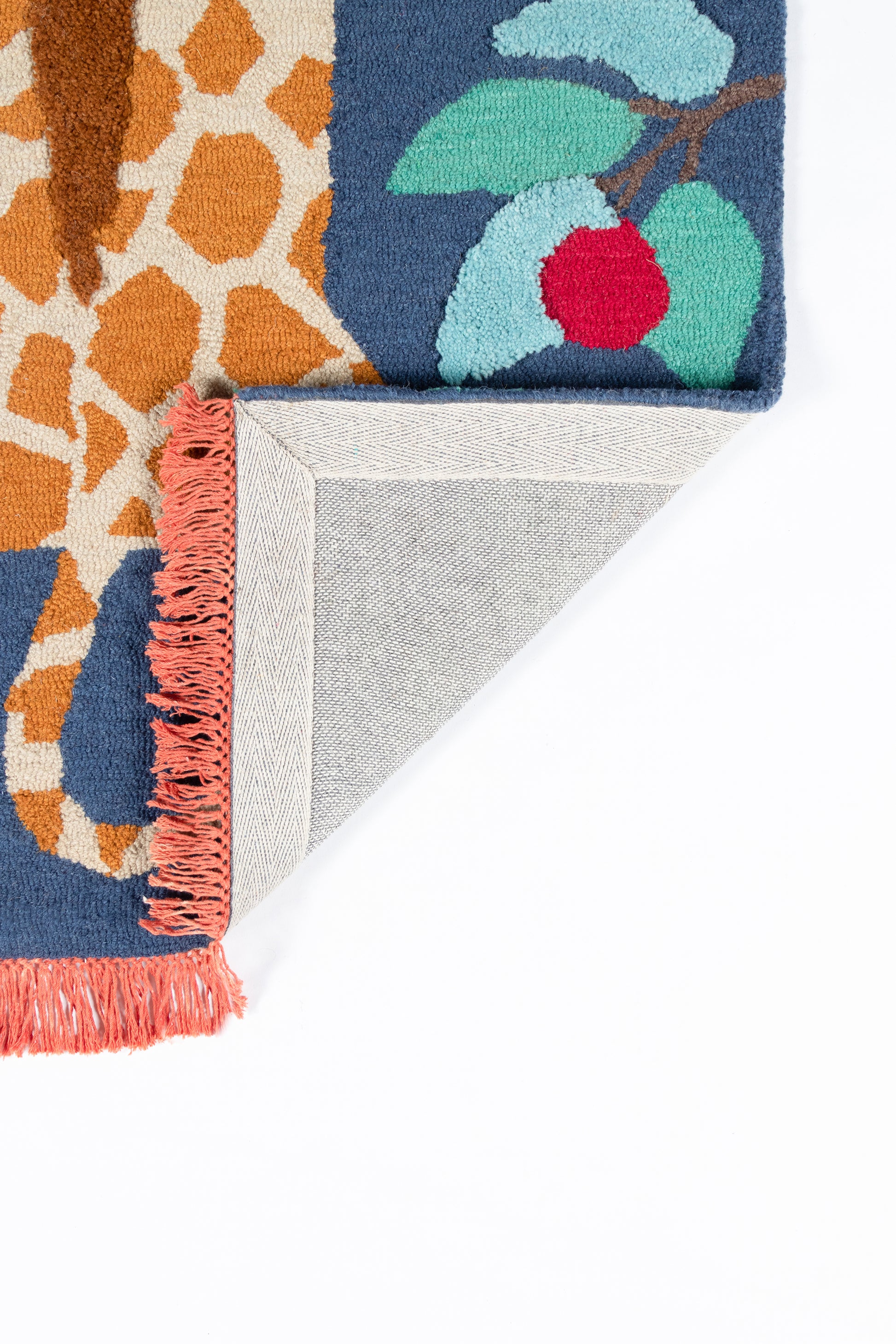 Vibrant woven rug with blue and orange sections, teal-red cherry motif; pink fringe, folded corner shows gray backing.