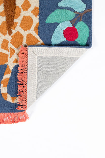 Colorful woven rug with navy blue and orange pattern, teal leaves, red berry, pink fringe; folded corner shows grey backing.