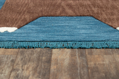 Brown rug with blue underside, teal fringe along bottom edge, laid on wooden floor.