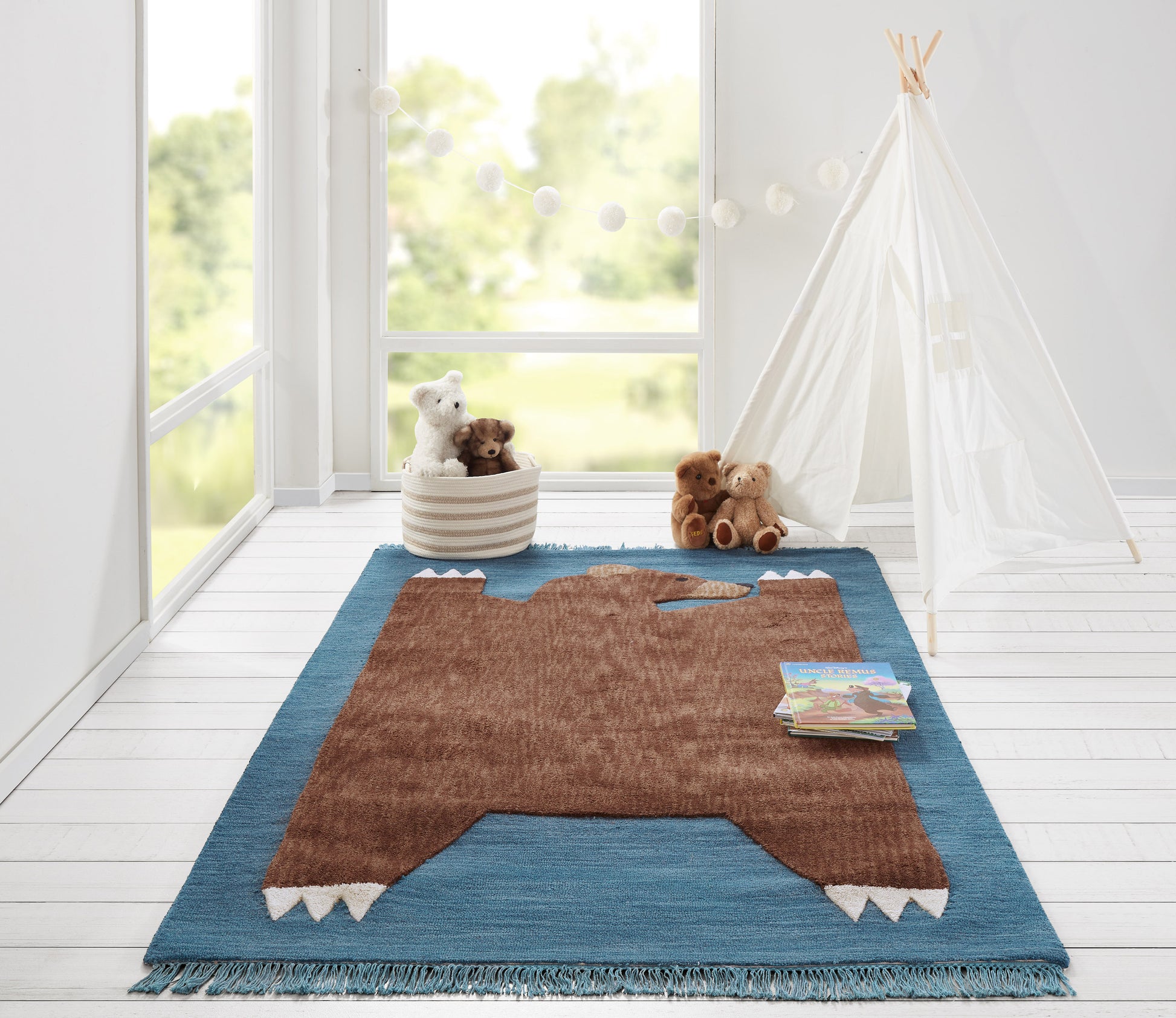 Brown bear-shaped shag rug with blue border and fringe, in a bright kids' room with stuffed animals and a white teepee.