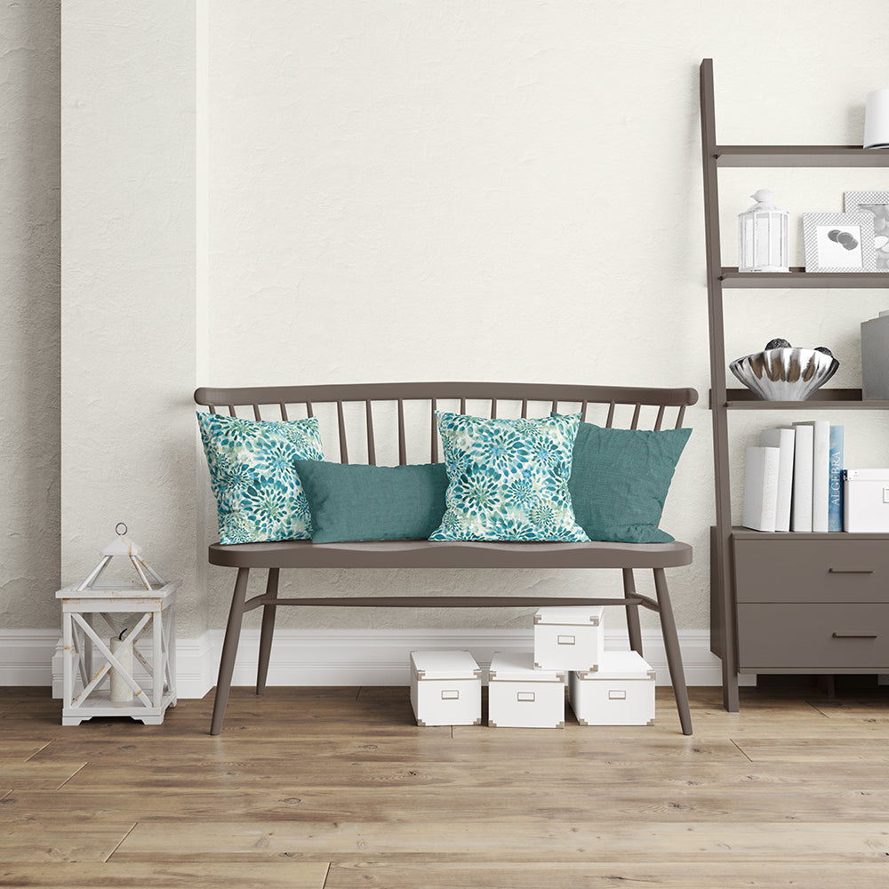 Dark brown metal-framed bench with wood seat and spindle back, teal and turquoise cushions in a cozy living room.