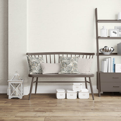 Dark brown wooden bench with slatted back and tapered legs, two floral cushions and two beige cushions in a neutral living room.