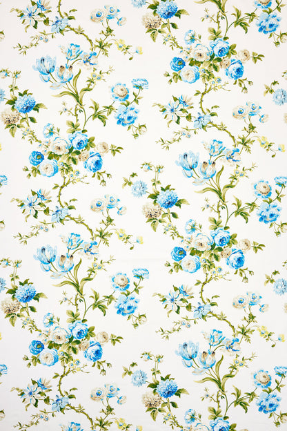 White fabric with blue flowers and green vines in a delicate botanical pattern