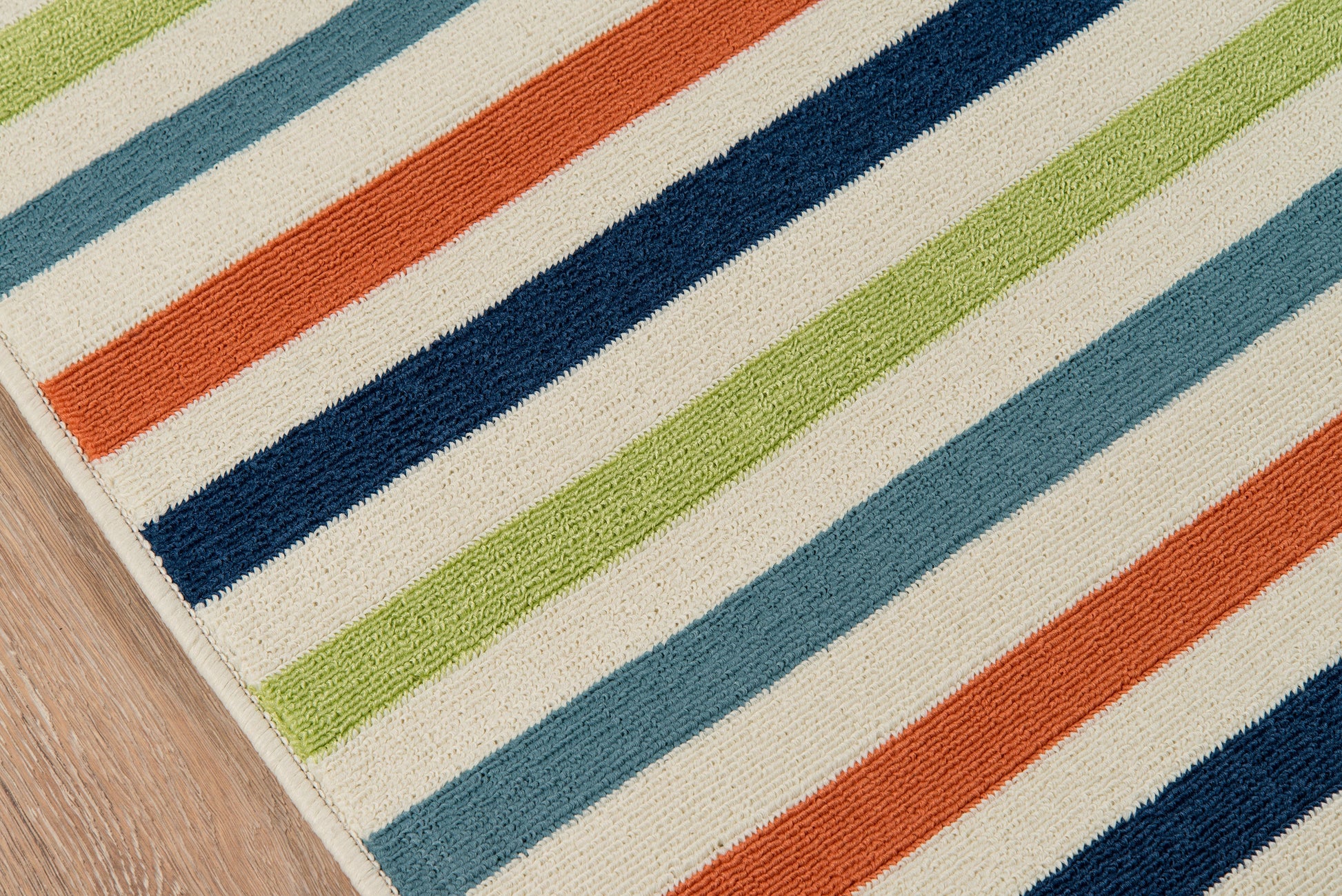 Striped rug with bold orange, navy, light blue, lime green and white stripes; textured loop pile on wood floor.