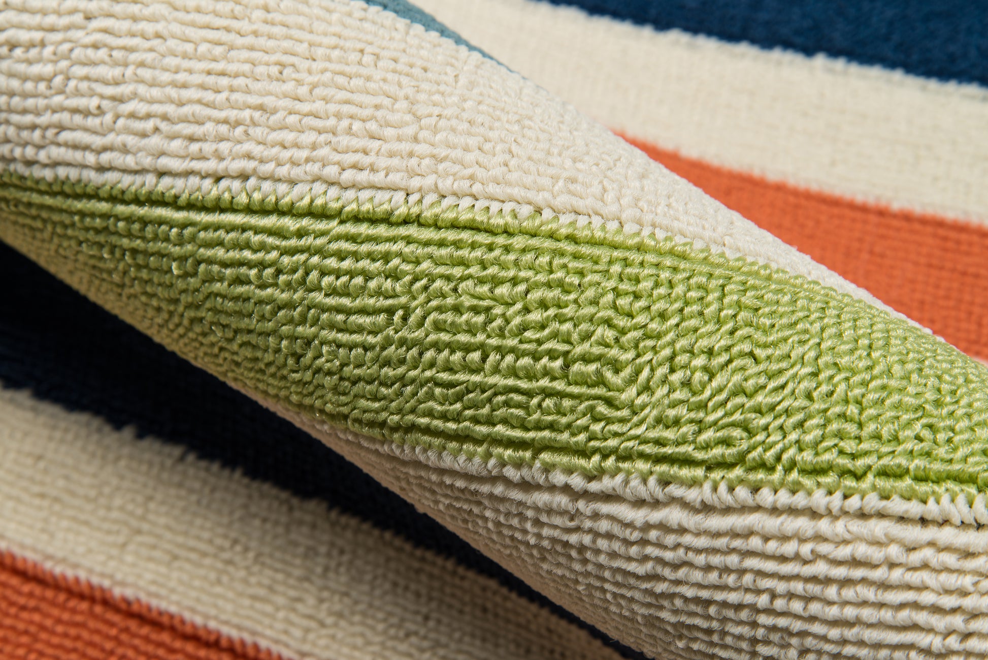 Folded striped terry towel in cream, lime green, orange and blue; soft woven cotton bath towel.