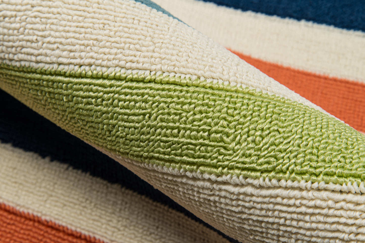 Close-up of a multicolor striped rug with lime green, cream, orange and navy blue bands; textured looped pile.