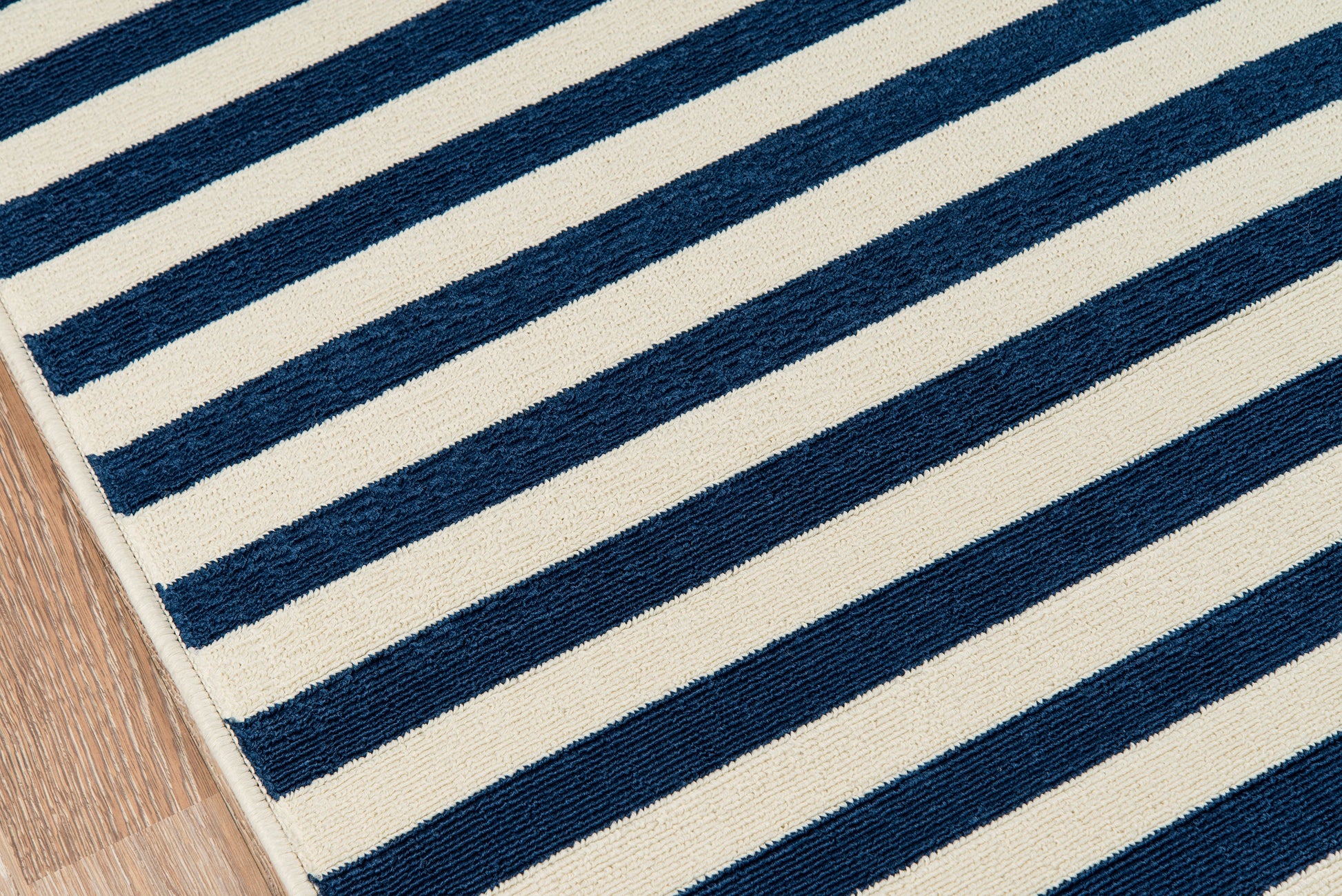 Blue and white striped woven rug with bold navy diagonal stripes on a wood floor.