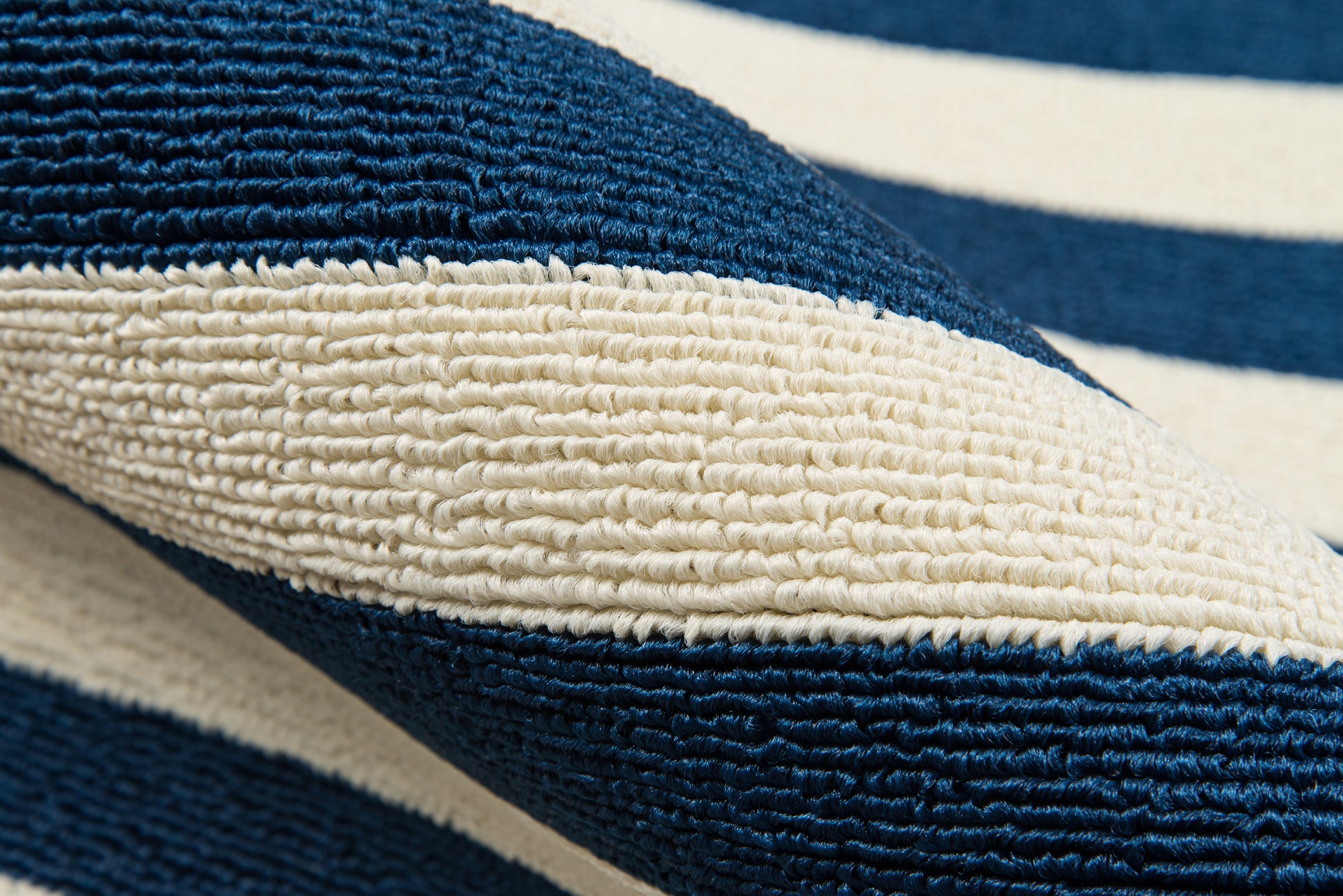 Close-up of navy blue and white striped woven rug with thick looped texture.