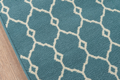Blue geometric rug with white trellis lattice pattern on a wooden floor.