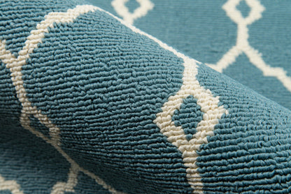 Close-up of turquoise-blue rug with white diamond trellis pattern and plush, textured pile.