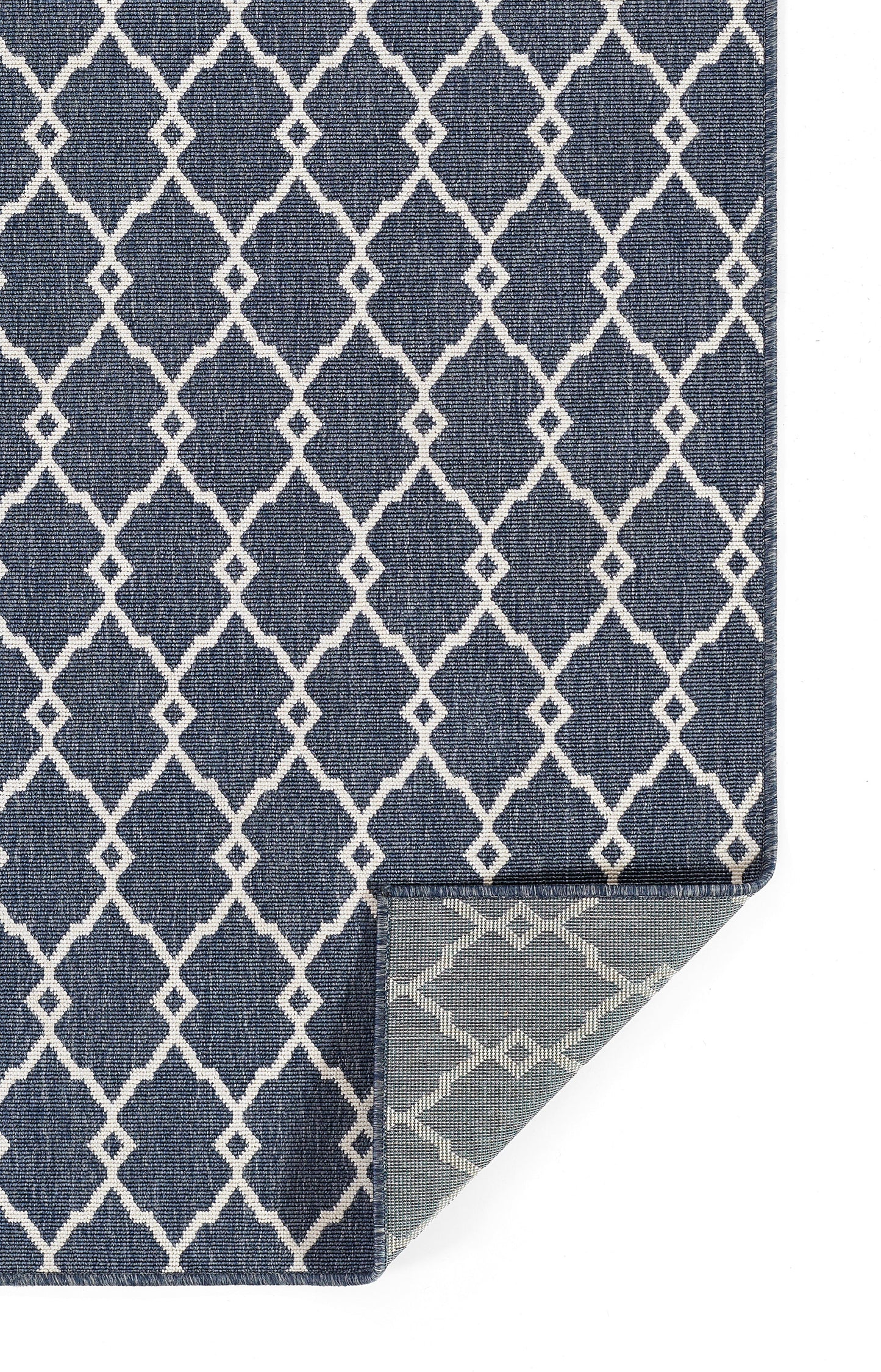 Navy blue rug with white lattice/trellis pattern; rectangular with a folded corner showing a light underside.