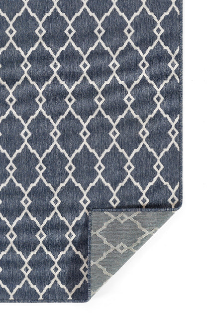 Navy blue rug with white lattice/trellis pattern; rectangular with a folded corner showing a light underside.