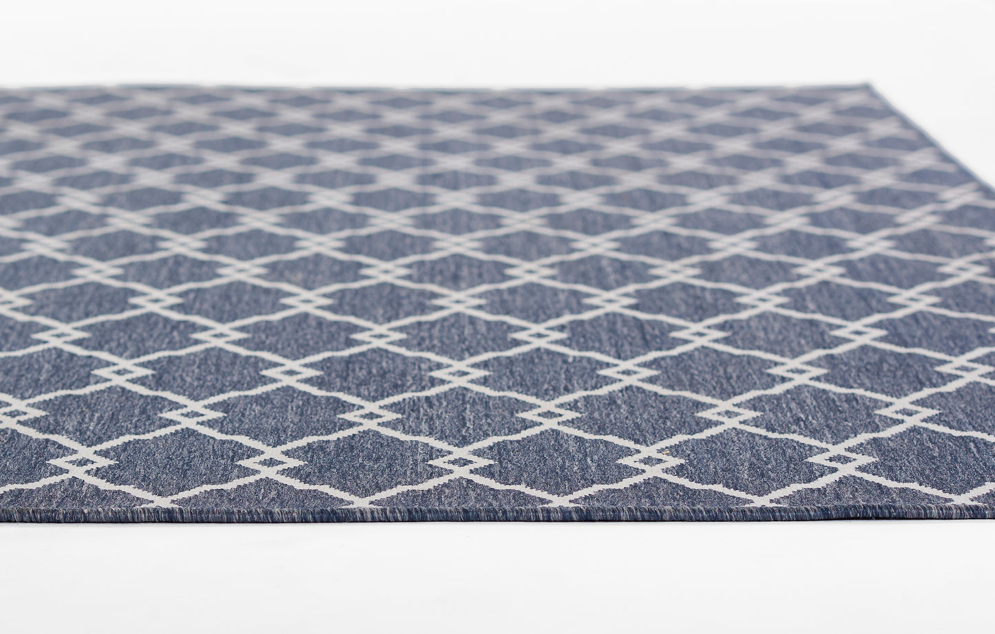 Navy blue flat-weave rug with white diamond lattice pattern; rectangular indoor floor decor