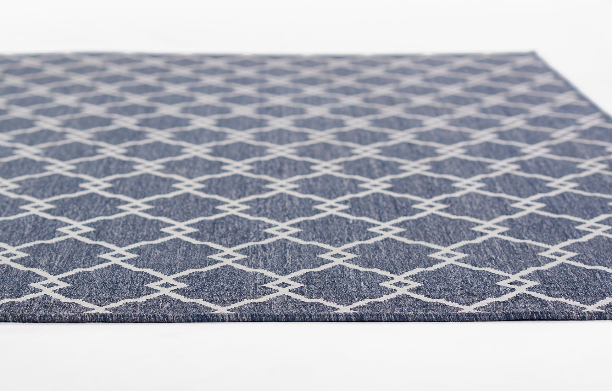 Navy blue flat-weave rug with white diamond lattice pattern; rectangular indoor floor decor