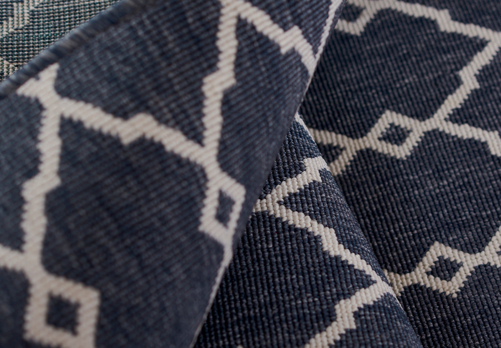 Dark blue woven rug with a white diamond lattice pattern; close-up.