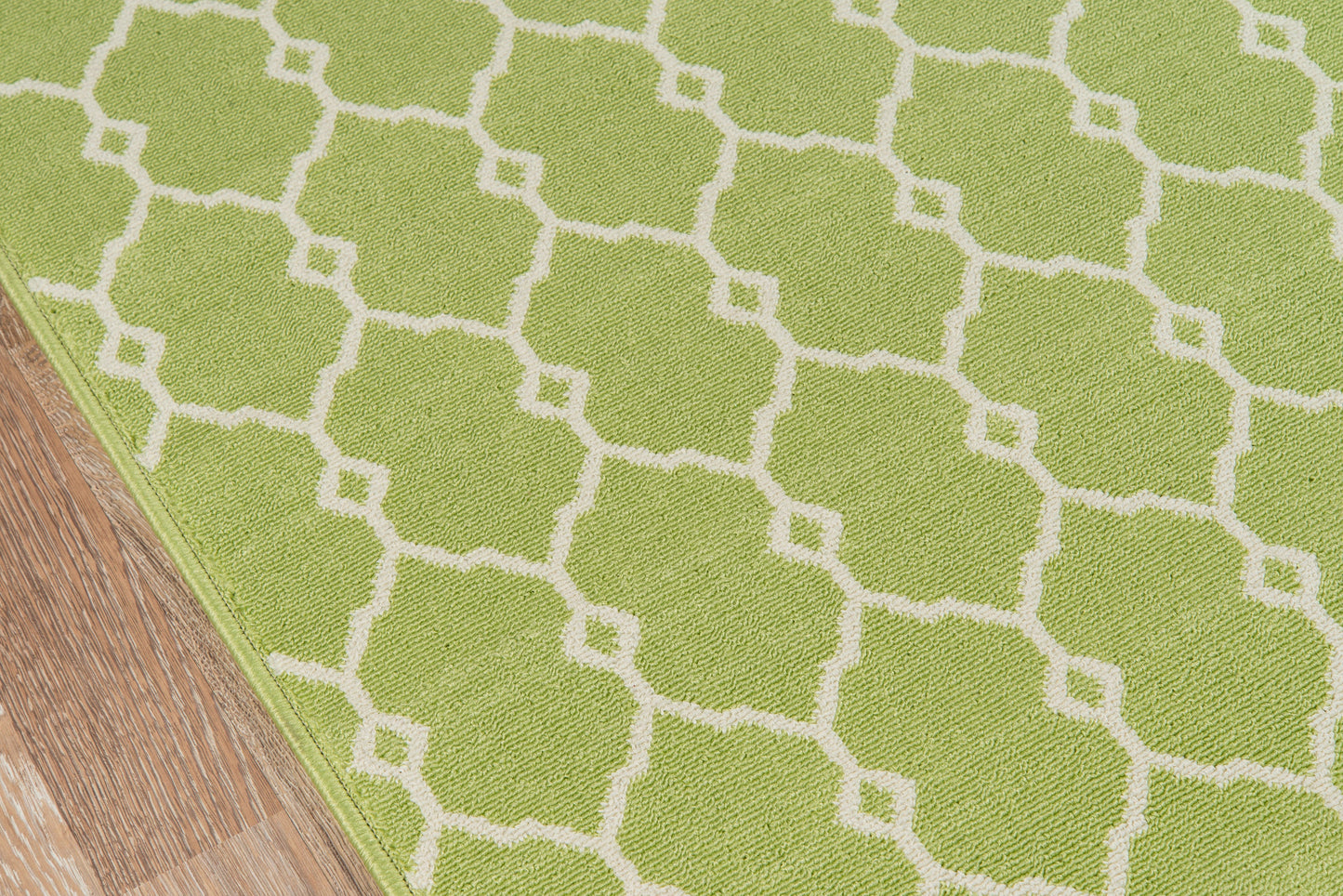Lime green rug with white trellis lattice pattern on wooden floor; low-pile, geometric style.