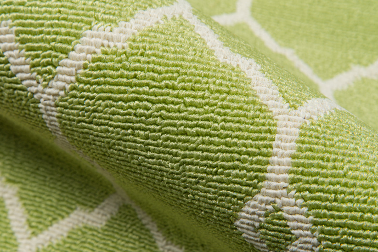 Lime green rug with white geometric lattice pattern; textured weave, close-up detail.