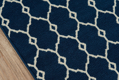 Navy blue rug with a white interlocking diamond trellis pattern; textured pile on a wooden floor.