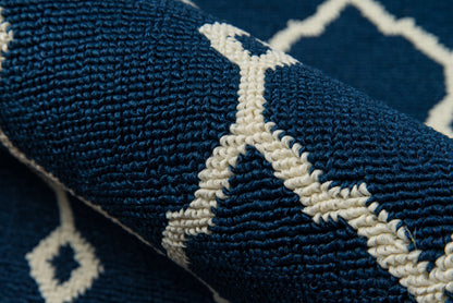 Close-up of a navy blue rug with white geometric lattice pattern; plush woven texture.
