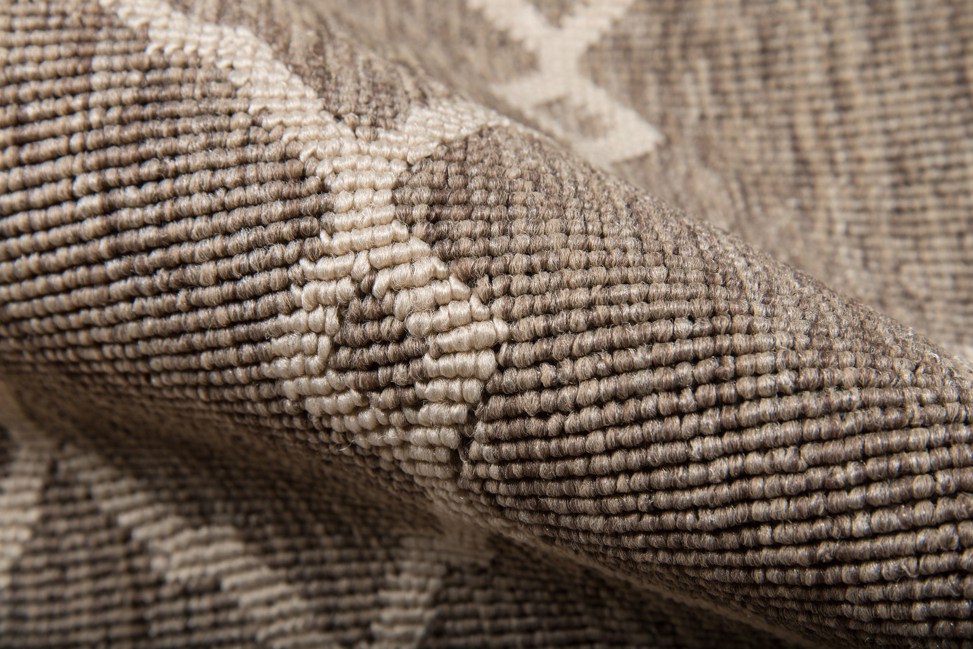 Taupe woven rug with cream geometric lattice pattern; close-up of textured, looped textile.