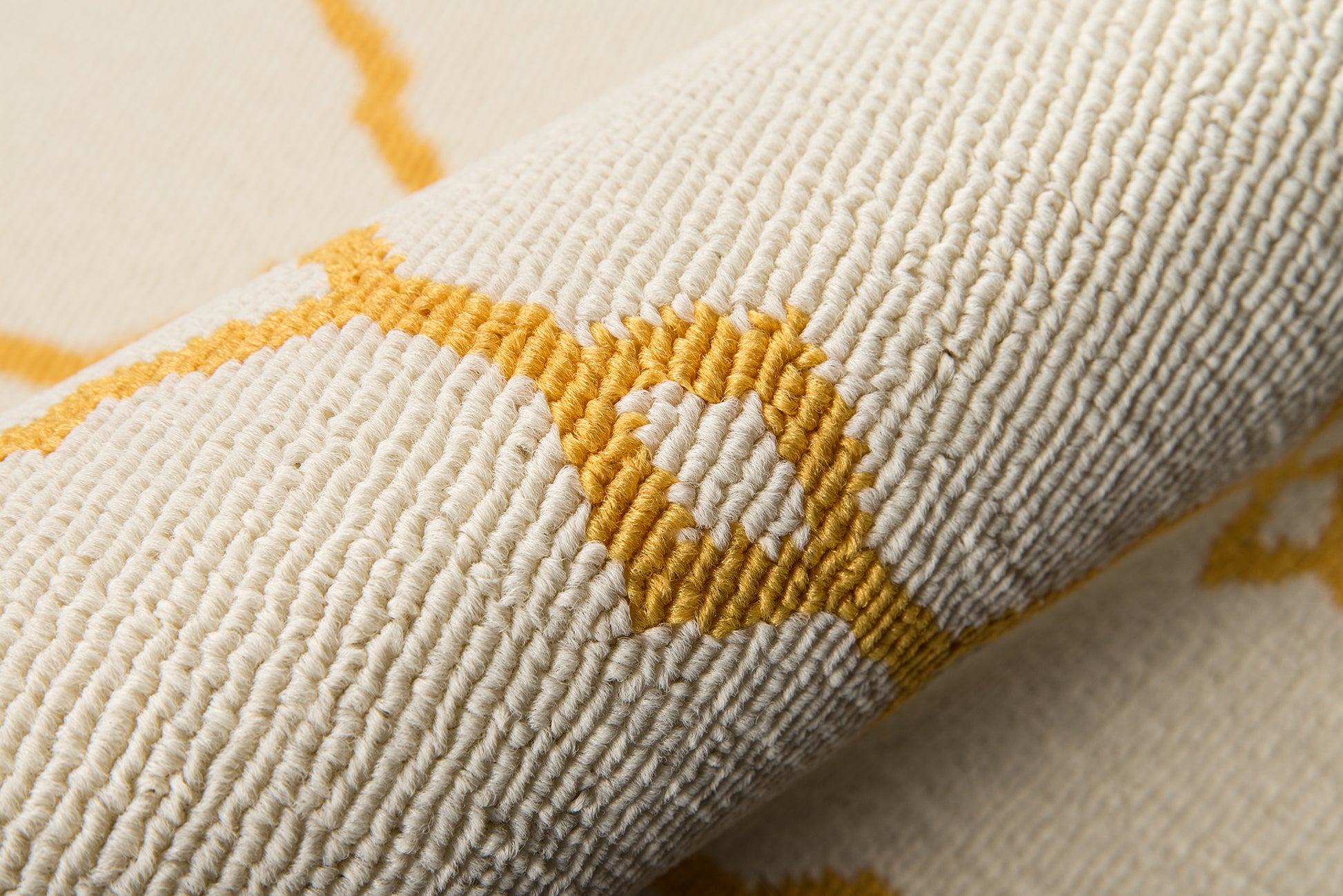 Beige textured rug with mustard-yellow geometric line and circle motif; close-up of woven looped fabric.