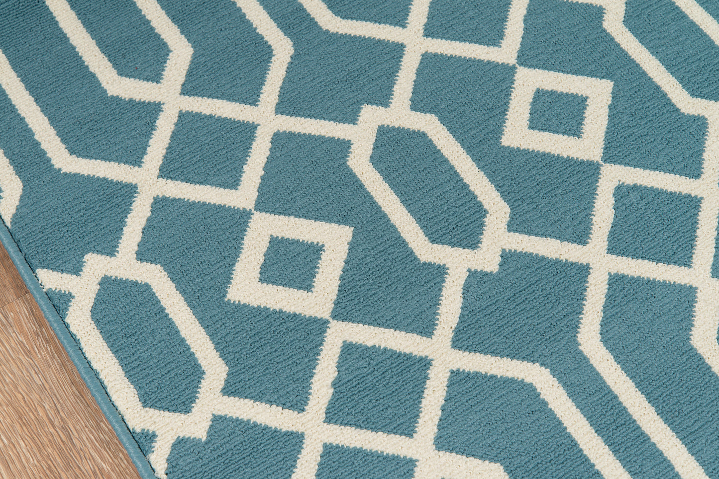Blue rug with white geometric lattice pattern on a wooden floor.