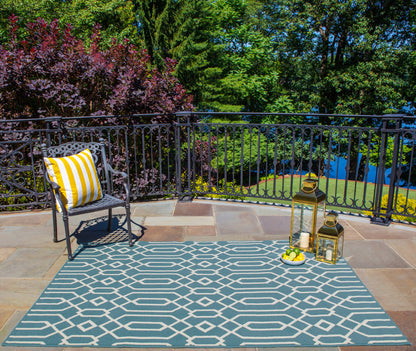 Outdoor balcony with a blue and white geometric rug, metal chair with a yellow striped cushion, lanterns and a lemon tray.