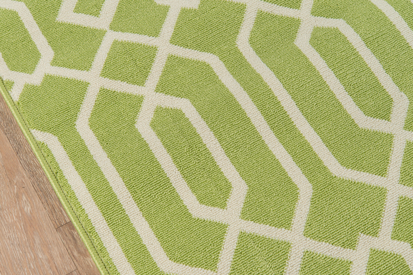 Lime green rug with white geometric lattice pattern, on a wooden floor.