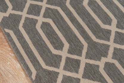 Gray area rug with cream geometric lattice pattern; modern low-pile rug on wood floor.