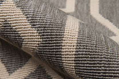 Close-up of gray woven rug with cream geometric stripes and textured loop pile