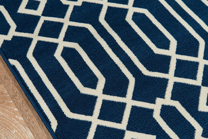 Navy blue rug with white geometric lattice pattern; plush textured pile on hardwood floor.