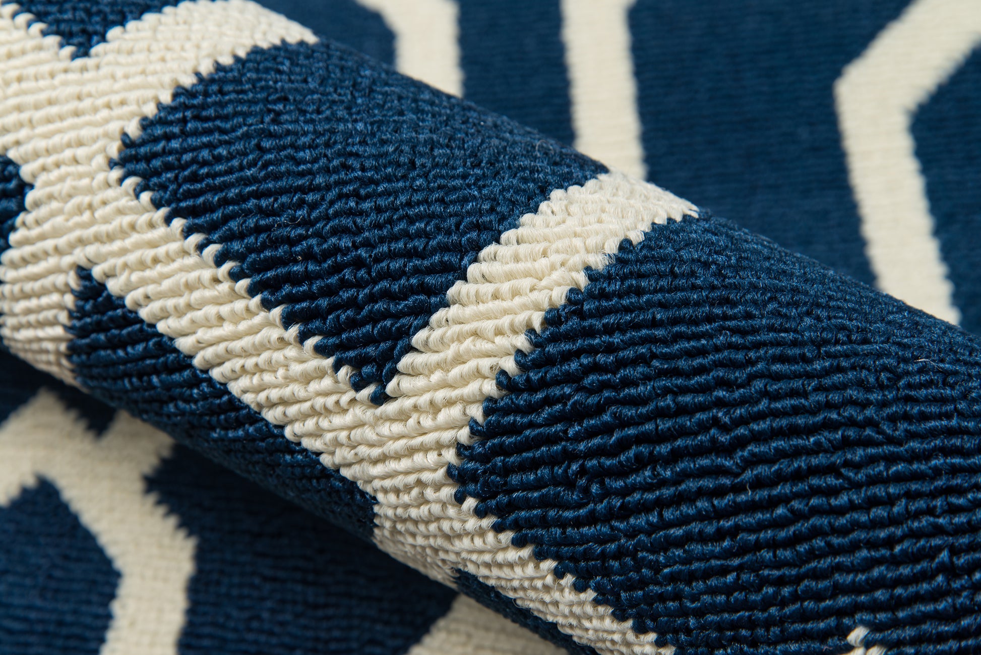 Close-up of navy blue and white woven rug with bold geometric chevron pattern and thick textured weave.