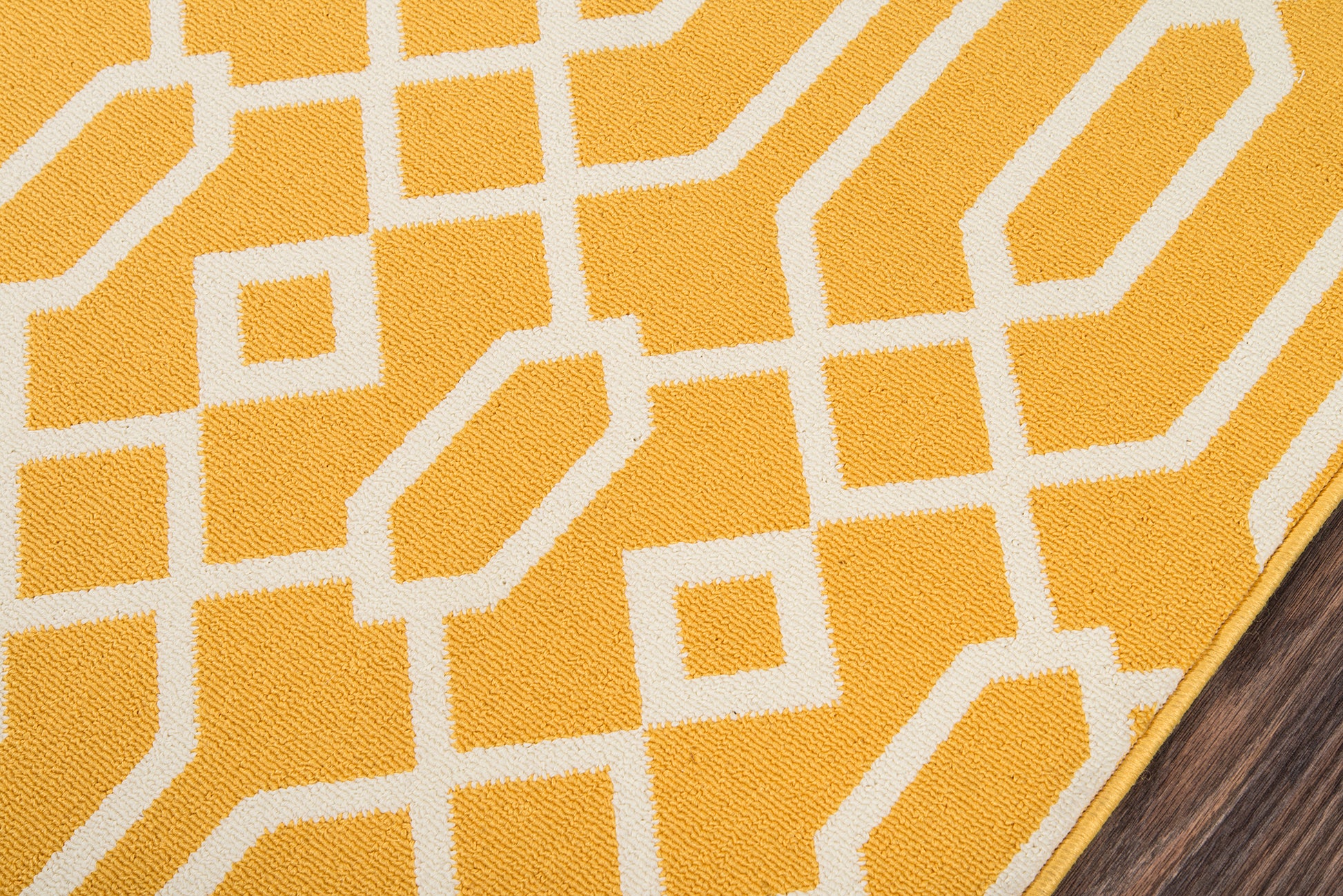 Yellow woven rug with white geometric lattice pattern; modern rectangular textile on wood floor.