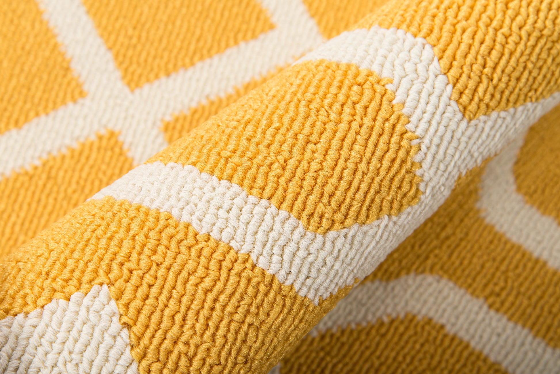 Close-up of yellow rug with white geometric stripes; looped pile texture.